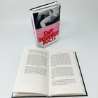 Gebundenes Buch mit Titel "Das Teufelsbuch". Vor ihm liegt es offen, die Seiten zeigen Text.