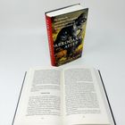 Das Buch "Der Arrogante Affe" von Christine Webb liegt offen, zeigt die Seiten 210-211 und steht aufrecht im Hintergrund.