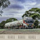 "Western Peak Group" auf einem Truck, Kalenderdarstellung 10/2021 unten. Ein großer Lastwagen auf einer Straße, umgeben von Bäumen.