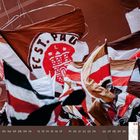 "FC St. Pauli" auf einer großen Fahne, darunter ein Kalenderabschnitt für April 2023. Zahlreiche Fahnen in Braun-Weiß-Rot.