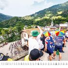 Unten steht: "4, SA MO DI MI DO FR SA". Menschen sehen Radrennen in bergiger Landschaft zu.