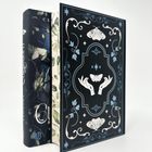 Dekoratives Buch-Cover und Schuber mit Blumen- und Blätterdesigns sowie weißen Motten und stilisierten Händen.