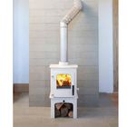 Ein weißer Ofen mit brennendem Feuer, silbernem Rohr und Holzlager davor, steht vor einer beigen Fliesenwand.