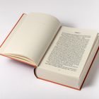 „Chapter 1“ steht oben auf einer aufgeschlagenen Buchseite. Das Buch hat einen roten Einband.