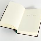 Text: "ERSTE EPISODE Die blonde Dame". Ein geöffnetes Buch liegt auf einem hellen Hintergrund.