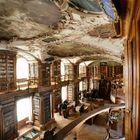 Holzgetäfelte Bibliothek mit kunstvoll bemalter Decke, Regalen voller Bücher und Menschen, die Stände betrachten.