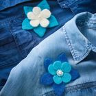 Zwei Jeanshemden mit Filzblumen-Ansteckern, eine in Blau, die andere in Weiß und Türkis.