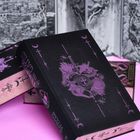 Auf einem schwarzen Buch steht in lila Schrift: "THE BOOK OF THE GATES". Verzierungen mit Schwertern und Monden.