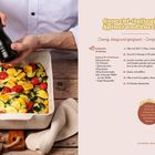 Gnocchi-Auflauf mit Spinat und Zucchini. Rezept mit Zutatenliste und Anleitung. Person würzt einen Auflauf mit Pfeffer.