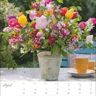 "April" steht oben links; darunter ein Kalender. Ein Blumenstrauß in einer Vase mit bunten Tulpen steht auf einem Tisch.