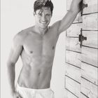 "04". Ein lächelnder Mann in weißen Shorts lehnt an einer Holzwand, muskulös und mit nassem Haar. Kalenderlayout unten.