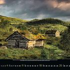 April 2023 Kalender. Zwei Holzhütten mit Grasdächern in einer grünen, bewaldeten Hügelandschaft unter bewölktem Himmel.