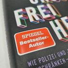 Roter Aufkleber mit "SPIEGEL Bestseller-Autor". Darunter bunte Buchstaben und kleinerer Text in Weiß und Lila.