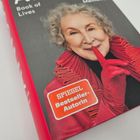 "SPIEGEL Bestseller-Autorin" steht auf einem roten Sticker. Eine lächelnde Frau trägt rote Kleidung und hält einen Finger vor den Lippen.
