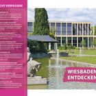 NICHT VERPASSEN! Wiesbaden entdecken: Bild zeigt modernes Gebäude mit Wasserbecken und Gras, Personen entspannen.