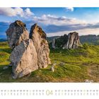 Kalender mit April hervorgehoben. Große Felsen in grüner Landschaft unter blauem Himmel mit Wolken.