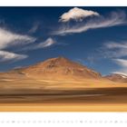 "APRIL 04 18 25." Sandwüste mit Bergen im Hintergrund, blauer Himmel und weiße Wolken.