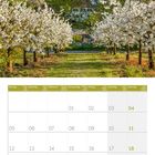 Kalender für April 2027. Blühende Obstbäume, Kirche und Berge in der Ferne im Hintergrund.