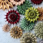 Verschiedene farbige, kunstvoll gefaltete Papiersterne auf grauem Hintergrund.