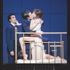 "Anna Karenina" und Daten im Kalenderformat. Ein Paar küsst sich leidenschaftlich auf einem goldenen Bett, ein weiterer Mann steht.