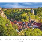 "Der Ort Camburg, Thüringen. Ein Dorf mit roten Dächern, umgeben von grünen Bäumen, einem Turm und einer Kirche."