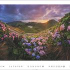 Aprilkalender: Eine Berglandschaft mit üppigen Hortensien und einem dramatischen Sonnenuntergang am Horizont.