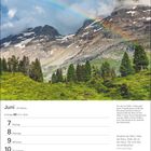 Juni, 23. Woche. Ein Regenbogen über einer alpinen Bergszene mit grünen Wiesen und Nadelbäumen.