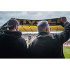 Zwei Personen im Stadion halten einen Schal mit der Aufschrift "DIE BESTEN FANS DER LIGA" hoch.