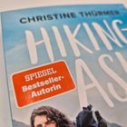 "SPIEGEL Bestseller-Autorin" steht im roten Feld, darüber "CHRISTINE THÜRMER HIKING ASIA" auf blauem Hintergrund. Unten unscharf: Person.