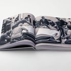 Ein aufgeschlagenes Buch zeigt ein schwarz-weißes Foto. Darauf arbeiten mehrere Personen an einem Sportwagen.