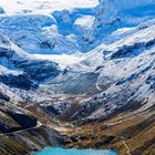 Keine sichtbaren Texte. Schneebedeckte Berge, Gletscher und ein funkelnder türkisfarbener See im Vordergrund.