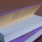 Ein Buch liegt offen, mit einem lilafarbenen Umschlag und einem Text auf der Innenseite der ersten Umschlagseite.