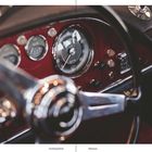 "The Maserati Book Milestones" unten. Nahaufnahme eines klassischen Autocockpits mit Tachometer und Lenkrad.
