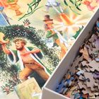 Illustration mit fröhlicher Szene: Eine Figur mit Füllhorn steht im Kranz, Puzzleteile liegen in einer Schachtel daneben.
