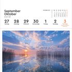 September Oktober KW 39. Kalender. Plauer See, Deutschland. Sonnenuntergang über einem ruhigen See mit Wolken und Schilf.