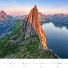 04, Segla, Senja, Troms. Hoher, schroffer Berg mit orangefarbenen Lichtflecken, umgeben von Wasser und grüner Landschaft.