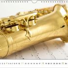 Kalender mit einer Nahaufnahme eines goldenen Saxophons auf Notenblättern. Unten schwarze Zahlen und der Monat April.