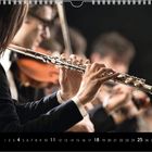 Kalender mit hervorgehobenen Daten: 4, 11, 18, 25. Musiker spielen Flöte und Violine, Fokus auf Flötenspiel.