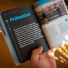 Seite 138 ist zum Thema "Frühstück" mit Tipps und einem Insider-Hinweis zum Essen in London. Zwei Hände halten das Buch.