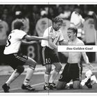 Text: "Das Golden Goal". Drei Fußballspieler feiern auf dem Spielfeld. Einer kniet jubelnd, die anderen umarmen ihn.