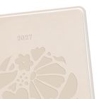 Text "2027"; beige Hintergrund, florale Muster auf einer Oberfläche.