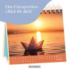 "Eine Extraportion Glück für dich! Feierabend: Kopf aus, chill mode on, Glück ahoi!" zeigt ein Papierboot im Sonnenuntergang.