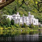 Kalenderbild von Kylemore Abbey, Benediktinerinnenabtei im grünen Wald; Reflexion im Wasser, Baum im Vordergrund.