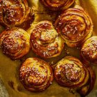 Keine Texte zu erwähnen. Mehrere goldbraune Zimtschnecken mit Zuckerstreuseln auf Backpapier.