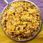 Reisgericht mit Bohnen, in einer Metallschale serviert. Der Hintergrund ist lila und gelblich.