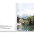 "3 Hausberg von Kranjska Gora" und Credits darunter. Eine Holzbrücke über klarem Wasser vor einem Hintergrund aus Bergen und Wald.