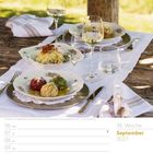 "36. Woche, September 2027. Knödeltrio und Weingläser auf gedecktem Tisch im Freien, sonnige Atmosphäre."