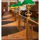 42 OKTOBER. Mo 18 Di 19 Mi 20 Do 21 Fr 22 Sa 23 So 24. Reihe grüner Lampen in einer Holzbibliothek.