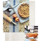 Text: "Apple crumble pie". Ein gedeckter Tisch mit einem Kuchen, zwei Äpfeln, Nudelholz und Mehl.