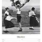 „Schuhplattler beim Tanz in bayerischer Tracht - Deutschland.“ Zwei Paare tanzen in traditioneller Kleidung. Text: Oktober.